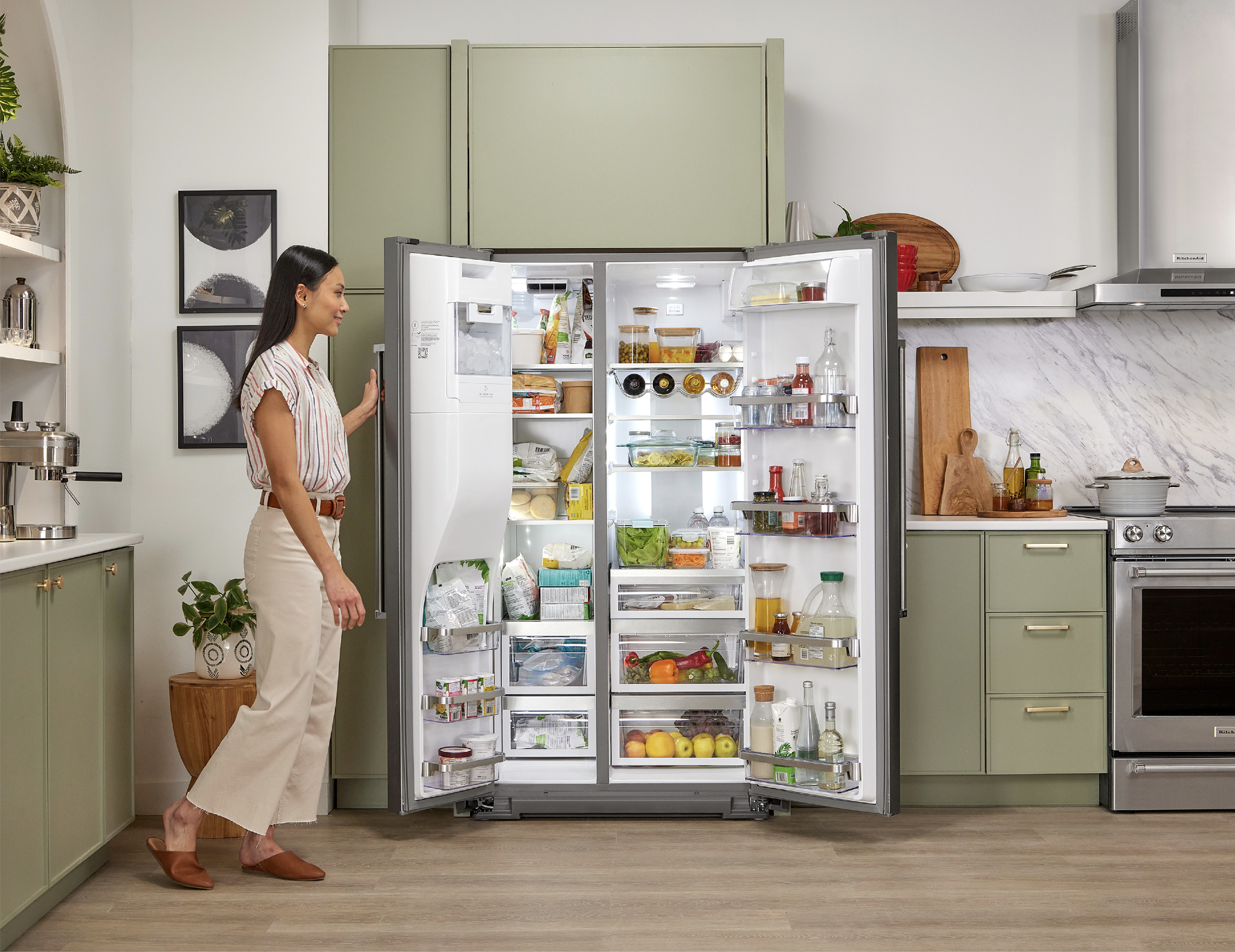 Woman standing next to an open side-by-side refrigerator